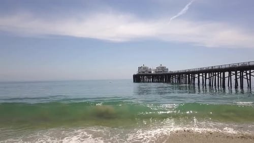 Wave breaks on the beach, flying along the landmark of Malibu Pier.
Spectacular aerial view flight f