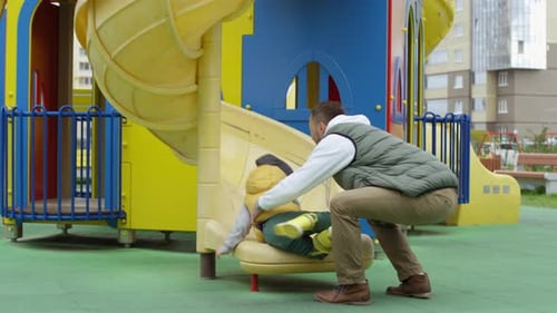 Kaukasische Eltern und Sohn haben gemeinsam Spaß auf der Spielplatzrutsche