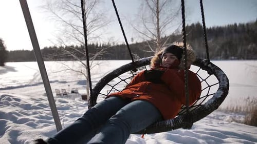 Woman Relaxing on a Swing in Winter Landscape