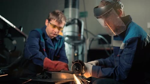 Workers Grinding Metal with Sparks in Dark Factory