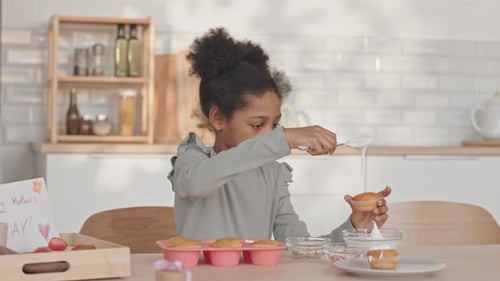 Child Decorating Cupcakes at Kitchen Table