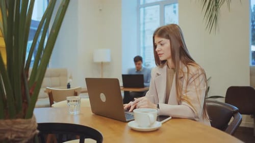 Female Freelancer Working on Laptop in Cafe