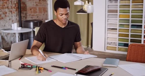 Young Adult Writes in Notebook at Table