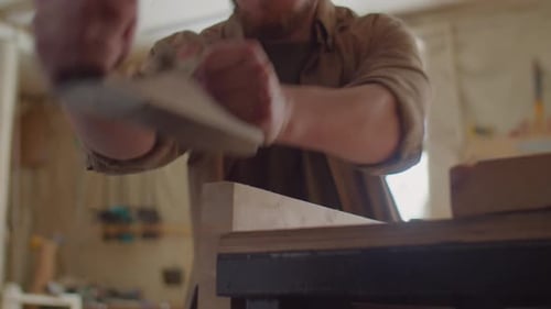 Man Woodworking in Workshop Using Hand Plane