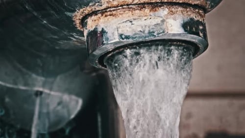 Water Flows From an Old Contaminated Tap with Calcium and Grime Into a Sink