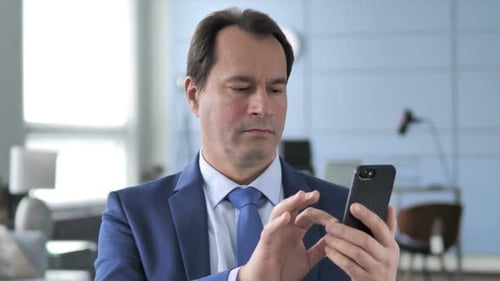 Businessman Using Smartphone in Bright Office Setting