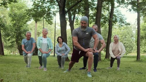 Group Fitness Class Doing Lunges in Urban Park