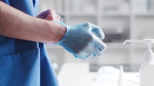 Close-up of doctor putting on gloves and cleaning hands using disinfectant with medical soap.