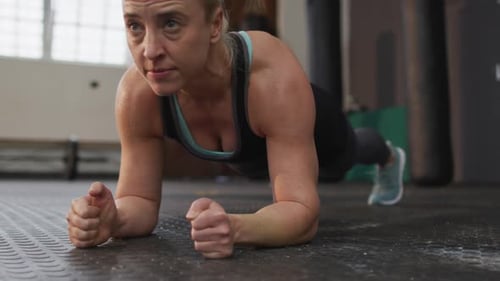 Close up of fit caucasian woman performing plank exercise at the gym