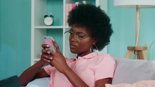 Young Woman Uses Phone on Couch at Home