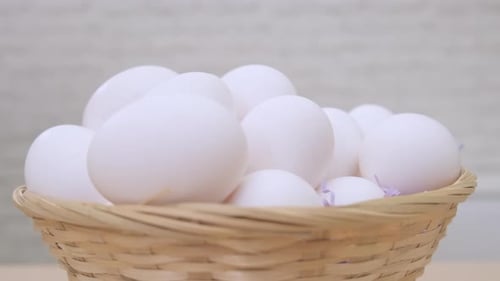 White Eggs Rotate in Basket on Light Background Close Up