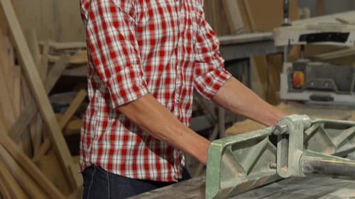 Happy Male Carpenter Posing with a Piece of Wood at His Workshop