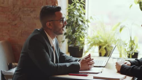 Male and Female Colleagues Speaking at Cafe Table on Lunch