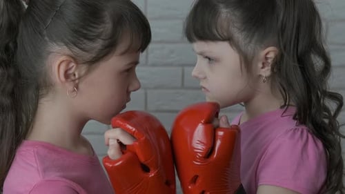 Kleine Mädchen in Boxhandschuhen schauen sich an