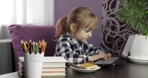 Young Child Types on a Laptop at Home