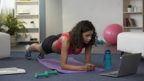 Junge Frau mit gemischter Rasse macht Online-Training vor Laptop, trainiert