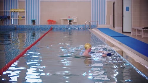 Swimming Instructor Teaching a Kid How to Swim in the Pool