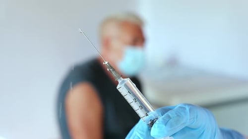 Close Up of Gloved Hand Holding Syringe