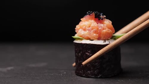 Take One Sushi Roll From Black Slate Board Using Chopsticks