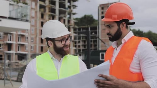 Construction Workers Discuss Blueprints at Construction Site