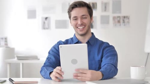 Young Man Video Calling with Tablet at Desk