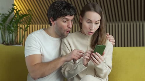 Excited Couple Looking at Mobile Phone Together