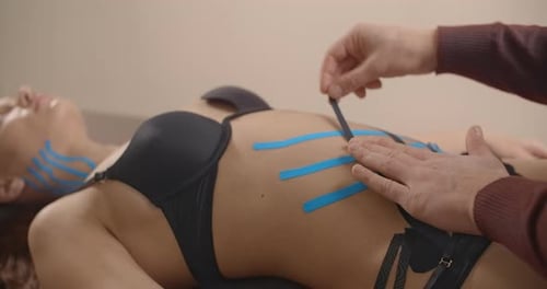 Applying Kinesiology Tape to Young Woman's Torso