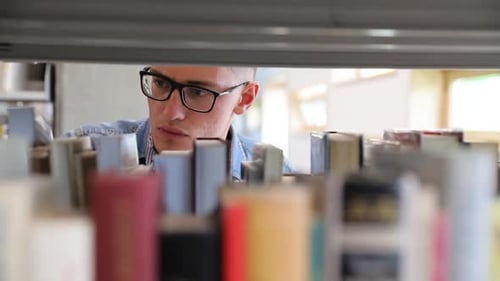 человек в библиотеке ищет книги на полках