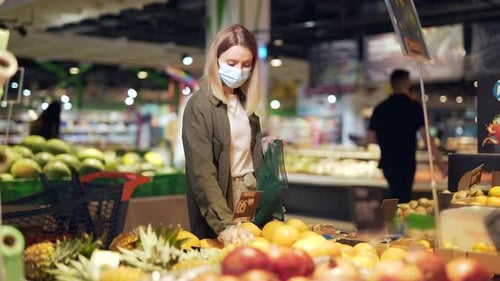 Woman Shops For Oranges Wearing Mask and Gloves