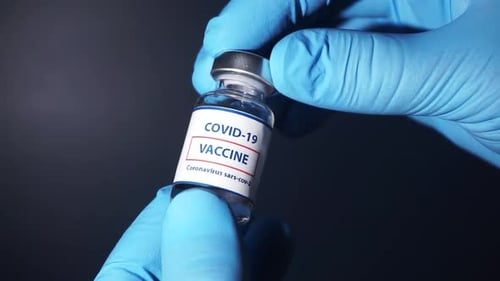 COVID-19 Vaccine Bottle Held in Gloved Hands
