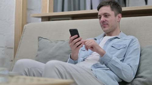 Man Using Mobile Phone Relaxing on Couch