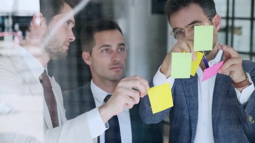Geschäftsleute brainstorming mit Post-its auf Glasscheibe