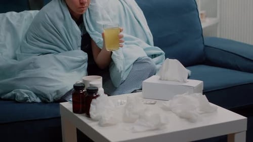 Woman Wrapped in Blanket Drinks Medicine