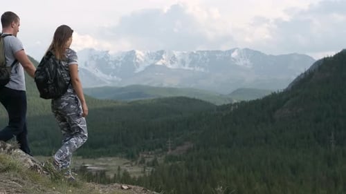 Una pareja exitosa, un hombre y una mujer llegan a la cima de la montaña y levantan las manos