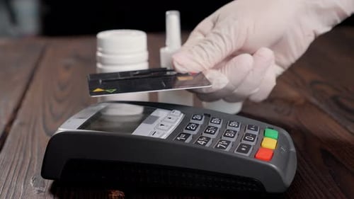 Closeup of a Woman in Gloves Paying for Medicines at a Pharmacy with a Card