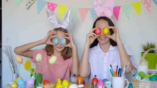 Mother and Her Little Daughter Painting Eggs. Happy Family Preparing for Easter.