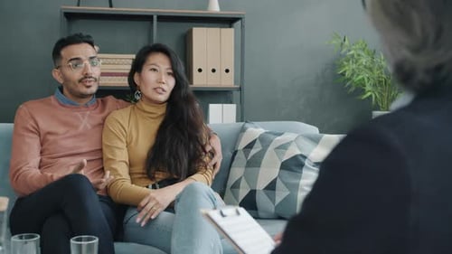 Glücklicher Ehemann und Ehefrau sprechen während einer Paartherapie-Sitzung im Büro mit einem Psychologen