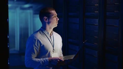A Young Man Works in a Data Center with Databases and Tests Equipment