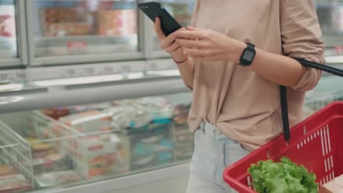 Woman Uses Smartphone While Grocery Shopping