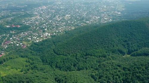 Vue aérienne du village dans la vallée derrière les montagnes couvertes d'une forêt verte dense