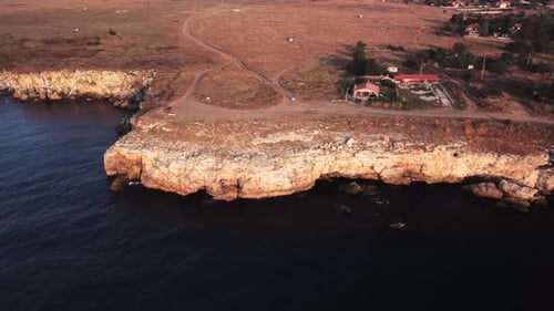 Drone top down aerial view of waves splash against rocky seashore, background. Flight over high clif