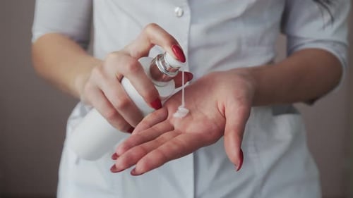 Close Up of Professional Beautician Shows How to Applying Body Lotion Cream on Hands