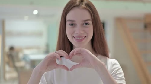 Smiling Woman Makes Heart Shape with Hands