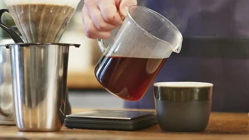 Pouring Hot Coffee To a Black Cup