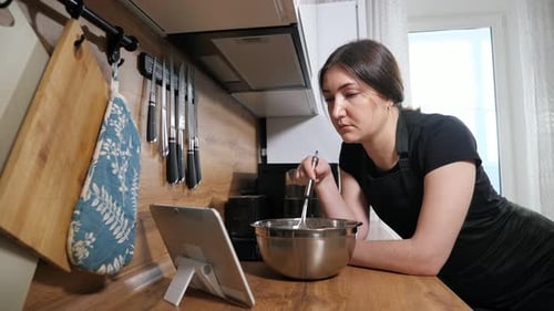 Woman Baking at Home With Recipe on Tablet