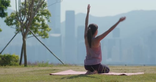 Woman Stretches in Park with City View