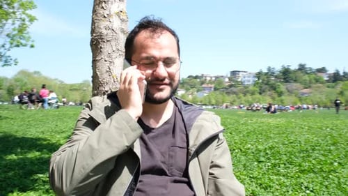 Man Talking on Phone in Sunny Park Setting