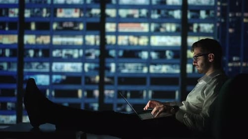 Focused Young Man Lying on the Sofa As He Works on His Laptop Late Into the Night