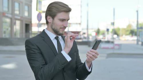 Young Adult Man Celebrates Using Smartphone on City Street