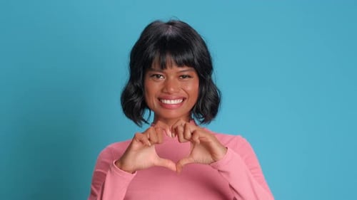 Woman Smiles Making Heart Shape with Hands